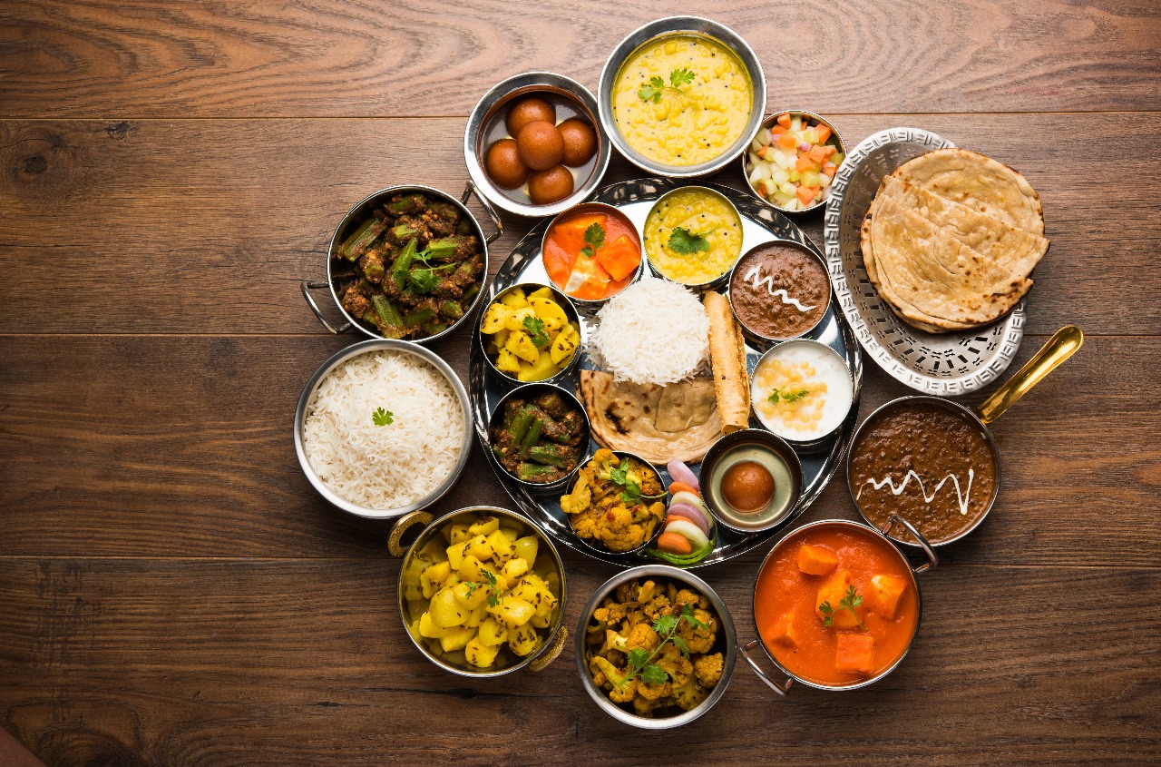 Indian Thali featuring rice, curries, roti, vegetables, desserts, and accompaniments arranged on a traditional platter